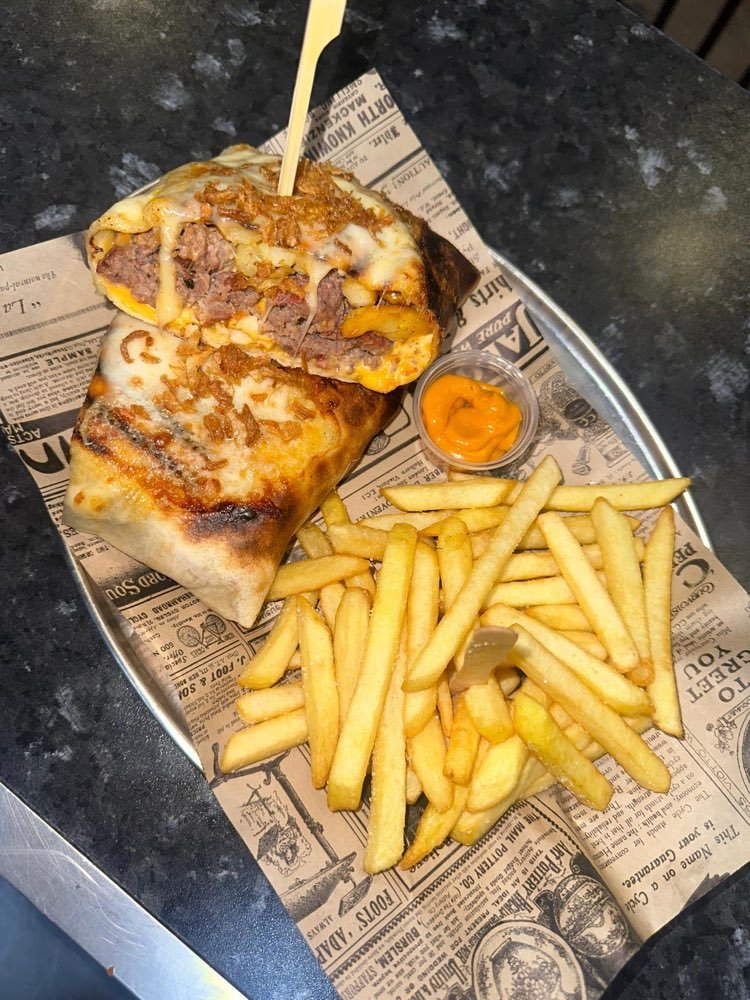 Bocadillo relleno gratinado con queso, cortado por la mitad, con patatas fritas